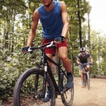 Two mountain bikers riding bike  in the forest on  dirt road.